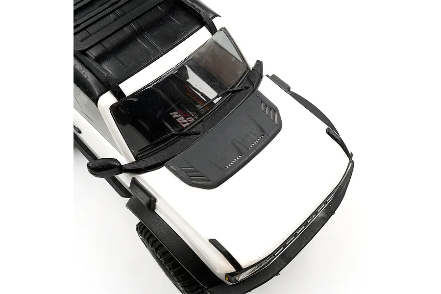 A close-up view of the hood of a white RC crawler vehicle featuring a black aftermarket engine hood intake accessory installed.