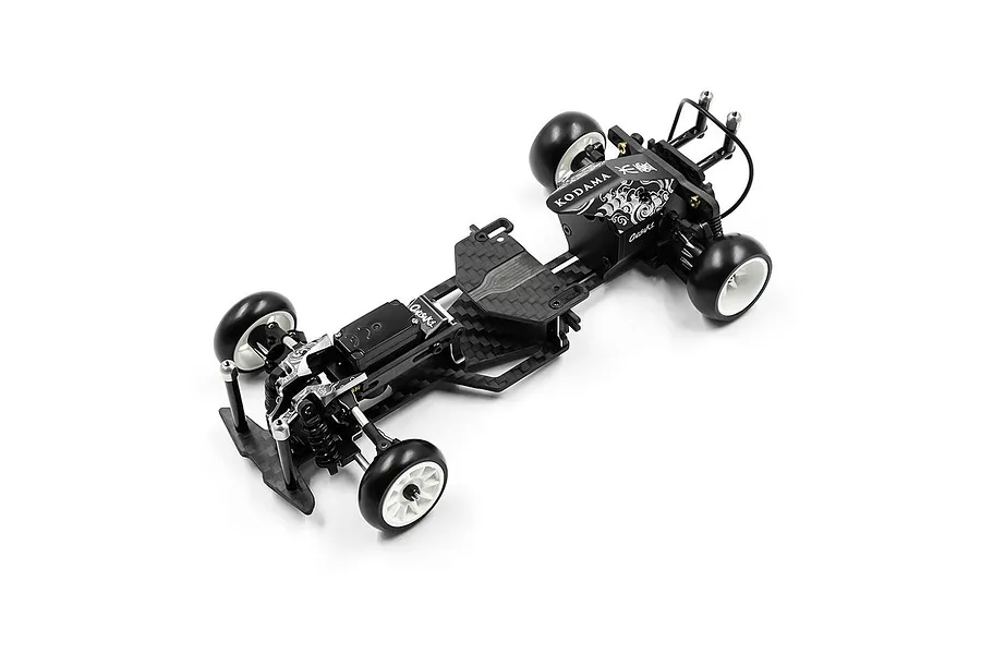 A high-angle studio shot of the Yeah Racing Onisiki Kodama 1/24 scale RC drift car chassis, featuring a carbon fiber frame and white drift wheels.