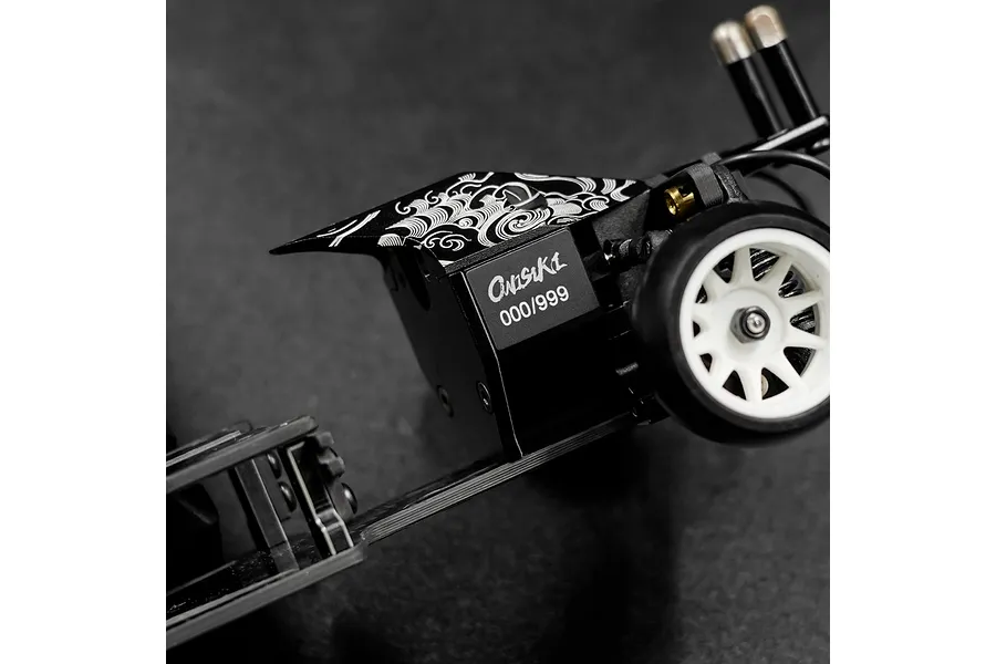 Close-up of an Onisiki Kodama RC drift car chassis showing the numbered serial plate and decorative wave pattern on the black frame.
