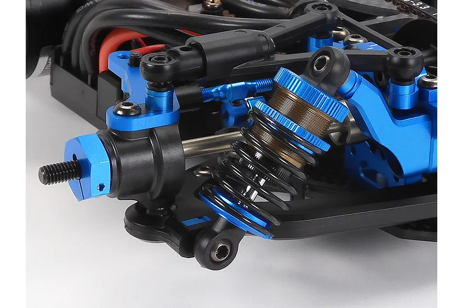Close-up of the front suspension assembly on a Tamiya TRF421 RC touring car, featuring blue anodized aluminum parts and a coil-over shock absorber.