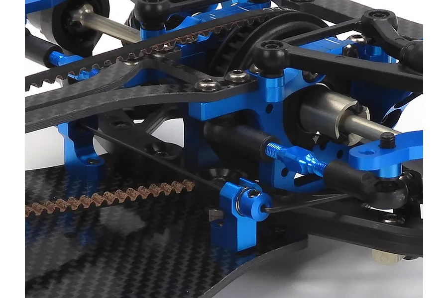 Close-up of the blue anodized aluminum and carbon fiber chassis components of a Tamiya TRF421 RC touring car kit.