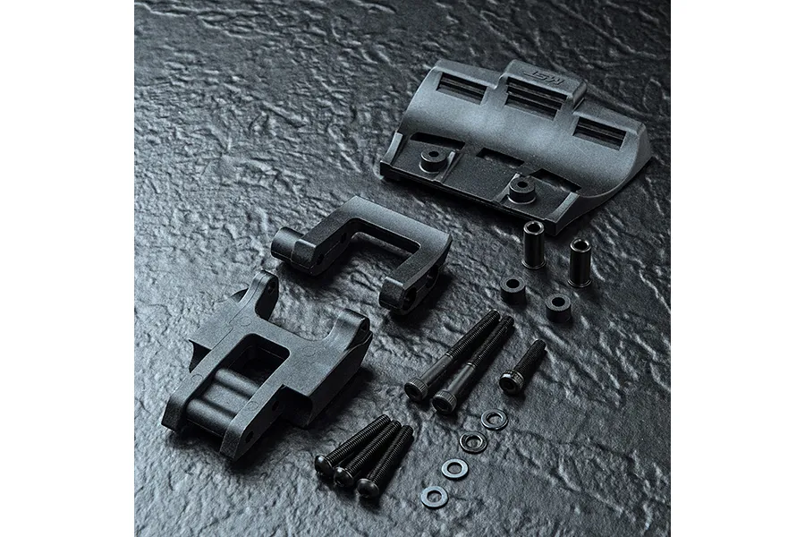 MST RRX conversion kit parts including molded plastic chassis components, screws, spacers, and washers arranged on a dark textured surface.