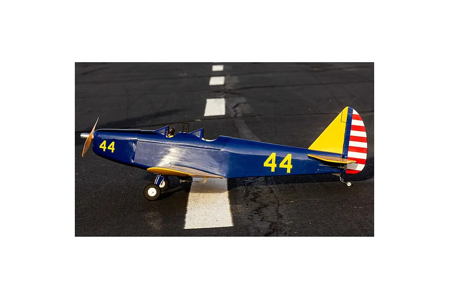A side profile view of a blue and yellow Hangar 9 PT-19 RC plane sitting on a paved runway with white markings.