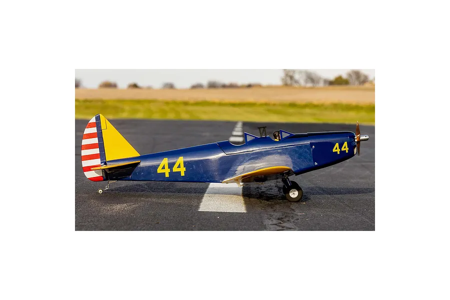 Side profile of a blue Hangar 9 PT-19 RC plane with yellow markings and number 44 on the fuselage, sitting on an asphalt runway.