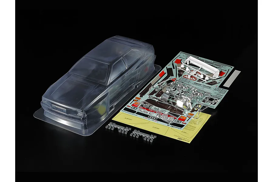 Tamiya 1/10 scale clear Audi Quattro Rallye A2 RC car body shell with included decal sheet, chrome-plated light buckets, and white rear wing parts.