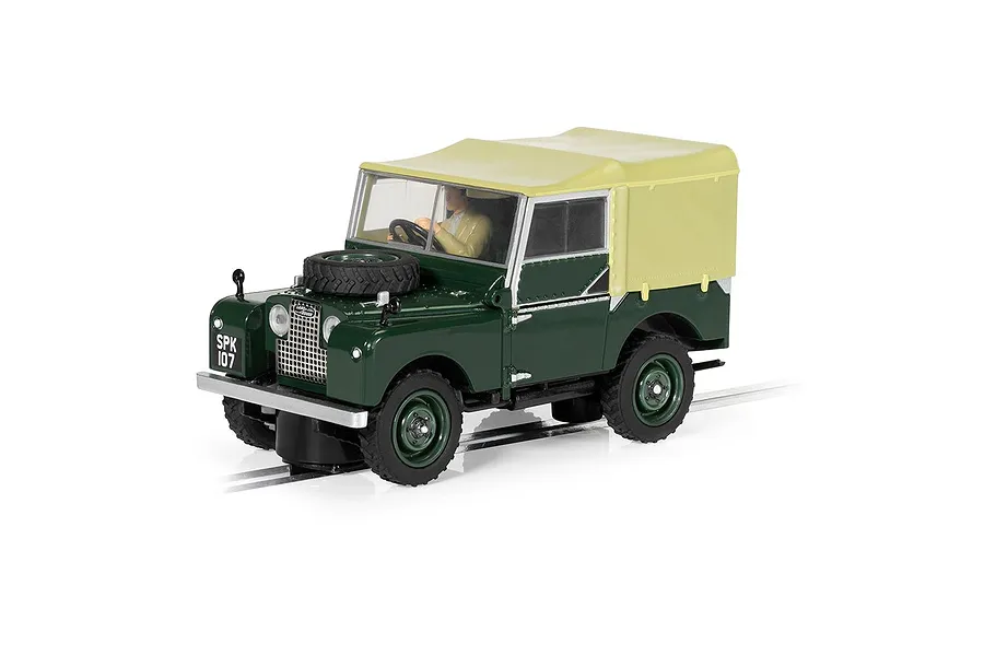 A 1/32 scale Scalextric Land Rover Series 1 slot car in dark green with a tan soft top, positioned on a slot car track.