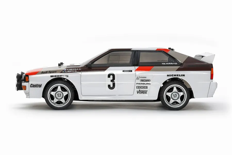 Side view of a Tamiya Audi Quattro A2 RC car kit on a white background, featuring white, brown, and red rally livery with number 3.