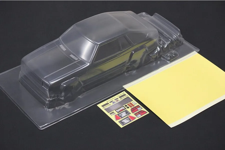An unpainted clear polycarbonate RC car body shell for a Nissan Sunny B310, including a decal sheet and masking film on a black background.