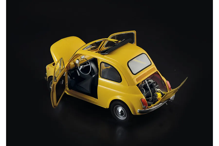 A high-angle studio shot of a yellow Italeri 1/12 scale Fiat 500 F model car with doors, hood, and engine cover open against a black background.