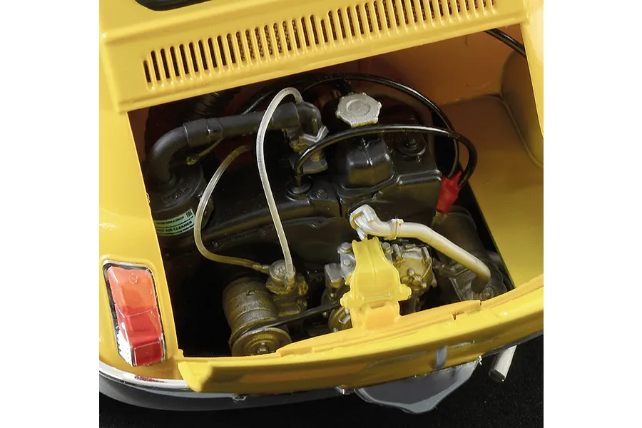 Close-up of the detailed engine bay of a yellow Fiat 500 F model car, showing the engine block, hoses, and rear taillight.