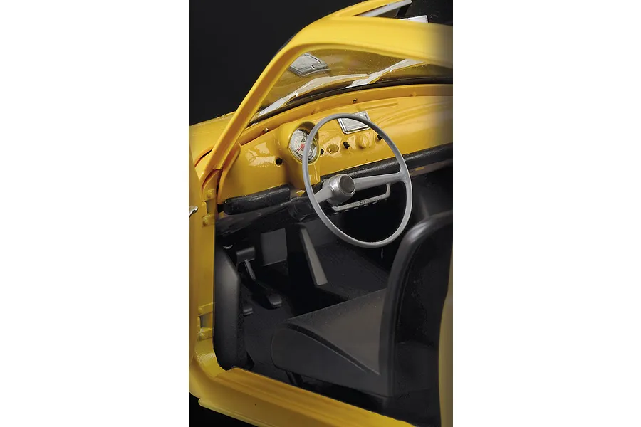 Close-up interior view of a yellow Fiat 500 F model car showing the dashboard, steering wheel, and front seat.