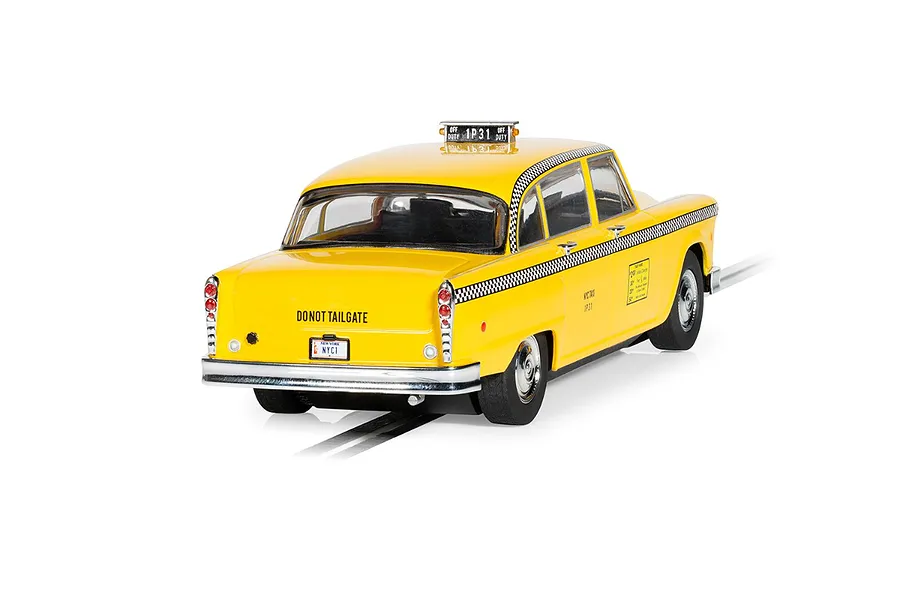 Rear three-quarter view of a yellow 1977 NYC taxi slot car by Scalextric on a white background.