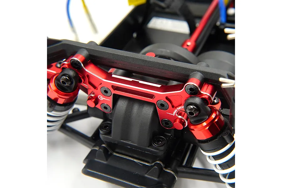 A red anodized aluminium shock tower installed on an RC car chassis, featuring Yeah Racing branding and black mounting screws.