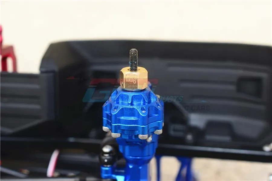 A brass 9mm offset wheel hex installed on a blue anodized aluminum RC car axle hub.