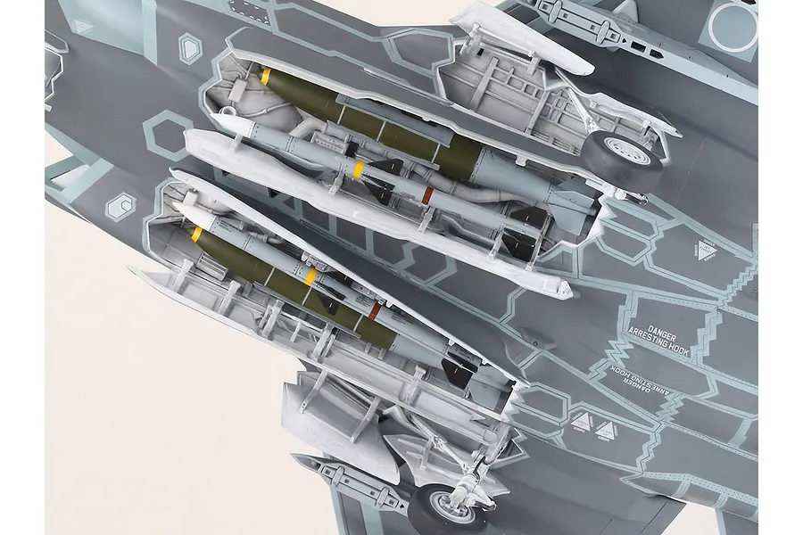 Close-up view of the underside of a Tamiya 1/32 scale F-35A model aircraft, showing open weapons bays with missiles and landing gear.