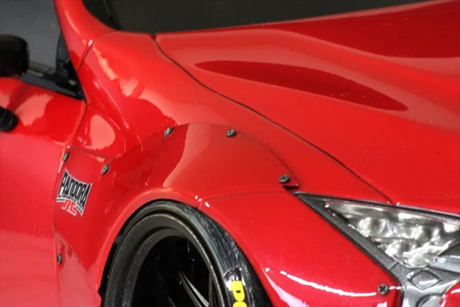 Close-up of a red RC car body shell featuring black over fender screws installed along the wheel arch.
