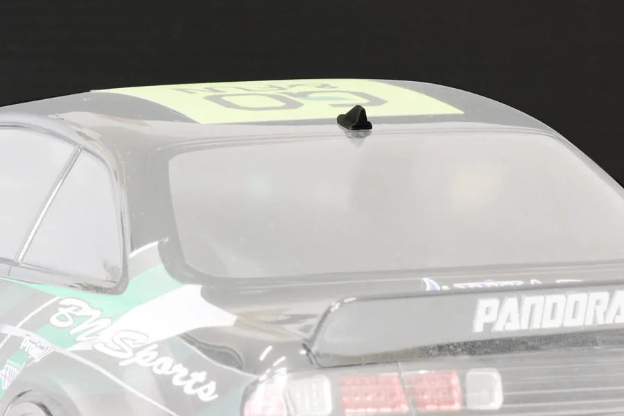 A small black shark fin style roof antenna mounted on the roof of a 1/10 scale RC car body shell.