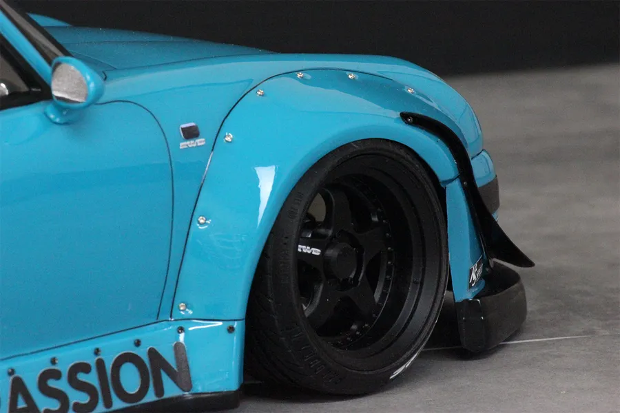 Close-up of a blue RC car body shell featuring silver over fender screws installed along the wheel arch.