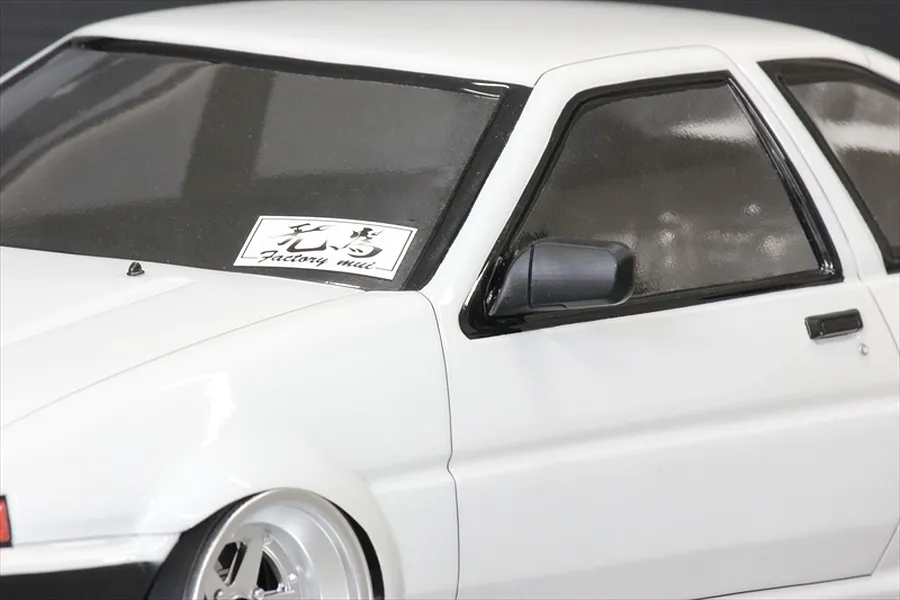 Close-up of a white 1/10 scale RC AE86 body shell featuring a black side mirror attached to the door.