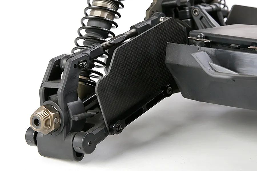 Close-up of a carbon fibre front suspension arm guard installed on an RC car, showing the weave pattern and mounting hardware.