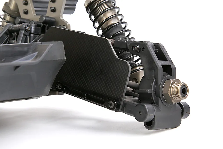 Close-up of a carbon fibre suspension arm guard installed on the front assembly of an RC vehicle against a white background.