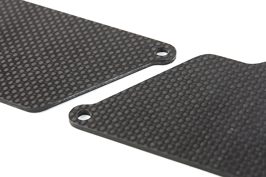 Close-up of two black carbon fibre RC suspension arm guards with a woven texture and mounting holes.