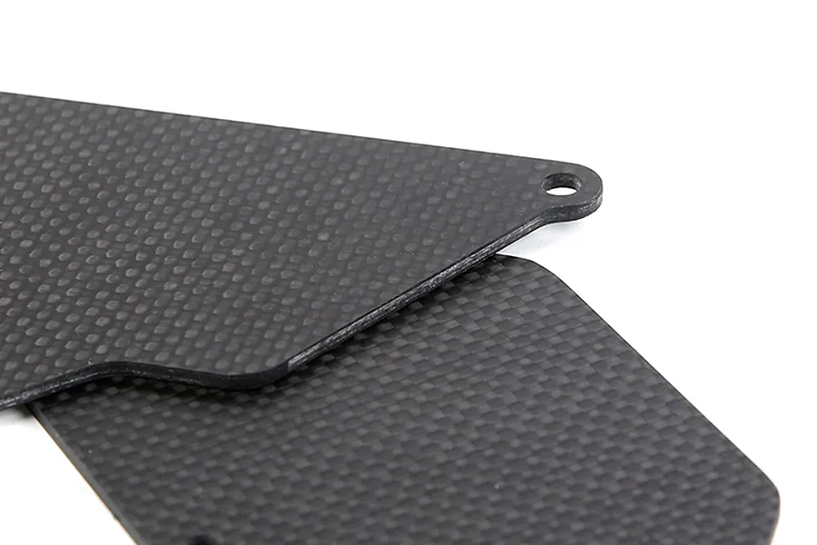 Close-up of two flat, black carbon fibre suspension arm guards with a woven texture and a mounting hole.