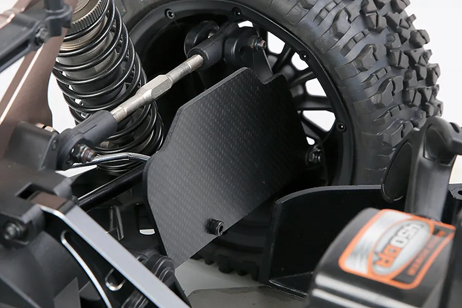 Close-up of a carbon fibre rear suspension arm guard installed on an RC vehicle, showing the weave pattern and mounting hardware.