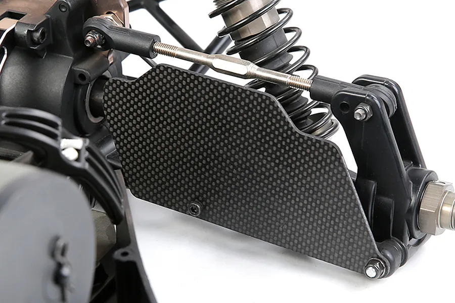 A close-up view of a carbon fibre rear suspension arm guard installed on an RC car chassis.