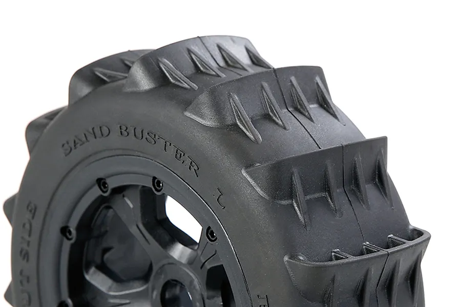 Close-up of a black RC paddle tyre with Sand Buster branding on a black beadlock rim against a white background.