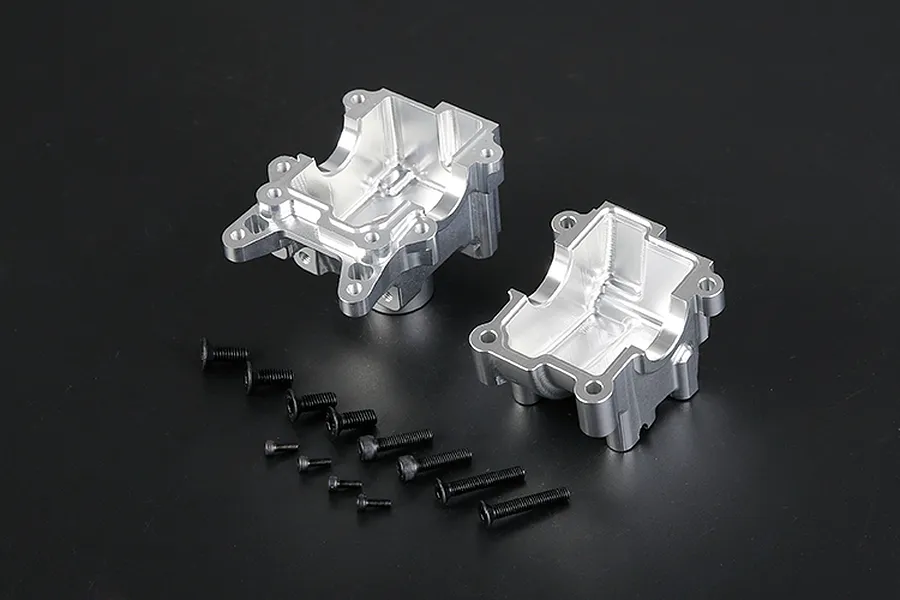 Two silver aluminium RC gearbox case halves with a set of black mounting screws on a dark background.