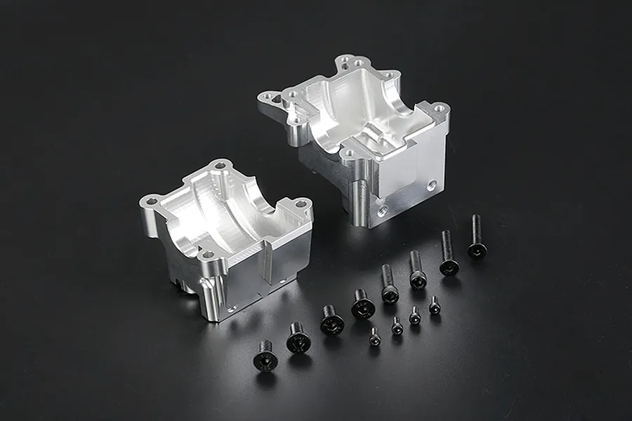 Silver aluminium RC gearbox case halves with a set of black mounting screws on a dark background.
