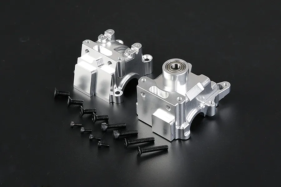 A pair of silver aluminium RC gearbox case halves with a set of black mounting screws on a dark background.