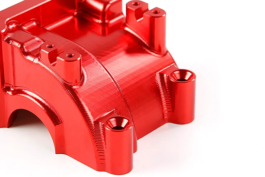 A close-up view of a bright red anodized aluminium RC gearbox case component with visible machining marks and mounting holes.