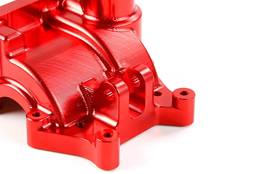 A close-up view of a red anodized aluminium gearbox case for an RC car, showing machined details and mounting points.