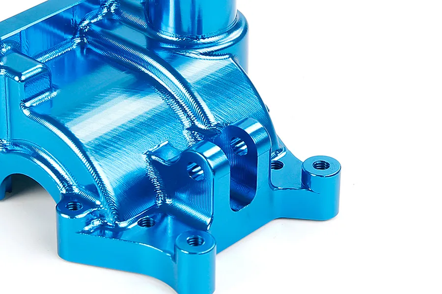 A close-up view of a bright blue anodized aluminium RC gearbox case showing machined surfaces and mounting points.
