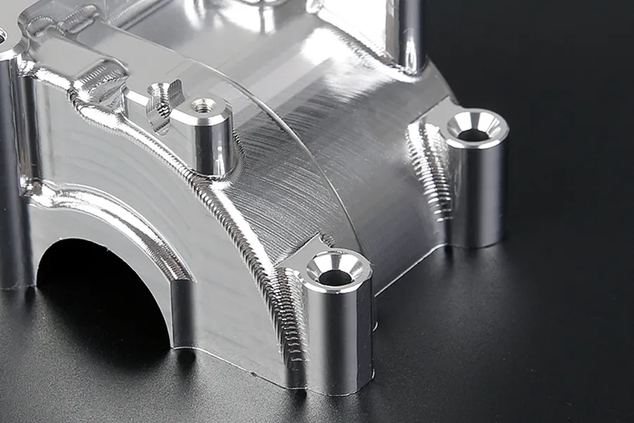 A close-up view of a silver Rovan aluminium gearbox case showing machined metal surfaces and mounting holes.