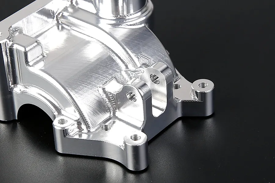 A close-up view of a silver Rovan aluminium gearbox case showing machined metal surfaces and mounting points.