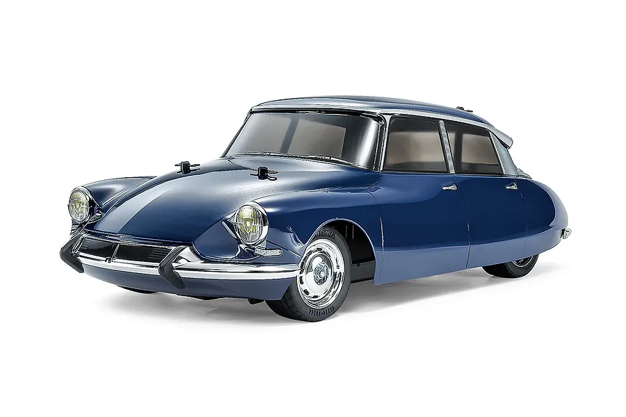 A studio shot of a 1/10 scale Tamiya Citroen DS RC car model in blue, featuring chrome bumpers and detailed wheels on a white background.