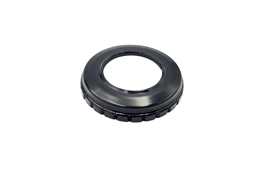 A black, circular RC shock top cap with a serrated outer edge, isolated on a white background.