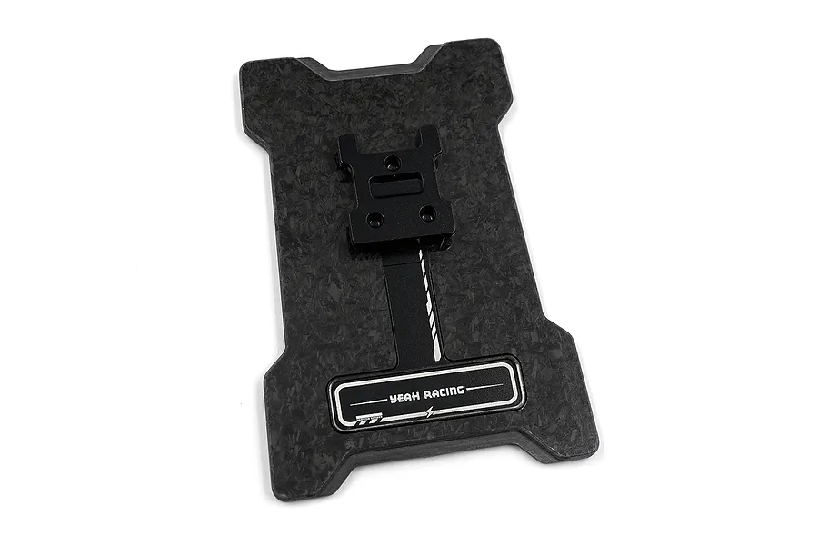 A black forged carbon fibre base plate for the FlySky NB4+ transmitter by Yeah Racing, featuring a central black metal mount and a branded logo plate.