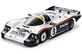 A studio shot of a Tamiya Porsche 956 RC car model with white, blue, and red racing livery, featuring the number 3 on the side.