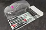 An unpainted clear polycarbonate RC car body shell of a Skoda Fabia RS, including a decal sheet, rear wing, and window masks on a dark textured surface.