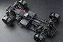 Top-down view of an MST RMX-M S Pro RC drift car chassis showing black plastic frame, red anodized shocks, and slick drift tires on a textured black surface.