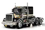 A studio shot of a black Tamiya King Hauler 1/14 scale RC truck kit with gold and white racing stripes on a white background.