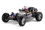 A Tamiya BB-01 BBX 1/10 scale 2WD RC buggy on a white background, featuring a blue body with racing decals, chrome wheels, and off-road tires.