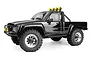 A black 1/18 scale HPI Venture18 1985 Toyota Hilux SR5 RC rock crawler truck with yellow off-road lights on a white background.