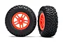 Two Traxxas 2.2/3.0 inch short course truck wheels with black off-road tires and bright orange split-spoke rims on a white background.