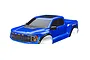A blue Traxxas Ford Raptor R RC truck body shell, pre-painted with detailed grille, headlights, and Raptor R branding, shown from a front three-quarter angle.