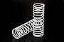 Two white Traxxas RC shock springs with yellow identification stripes, standing against a black background.
